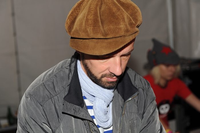 Shantel wearing a brown cap and scarf, looking down.