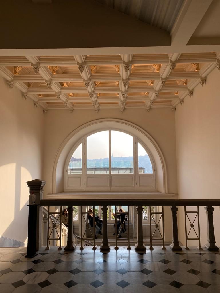 A large arched window and ornate ceiling above a landing inside Salt Galata.