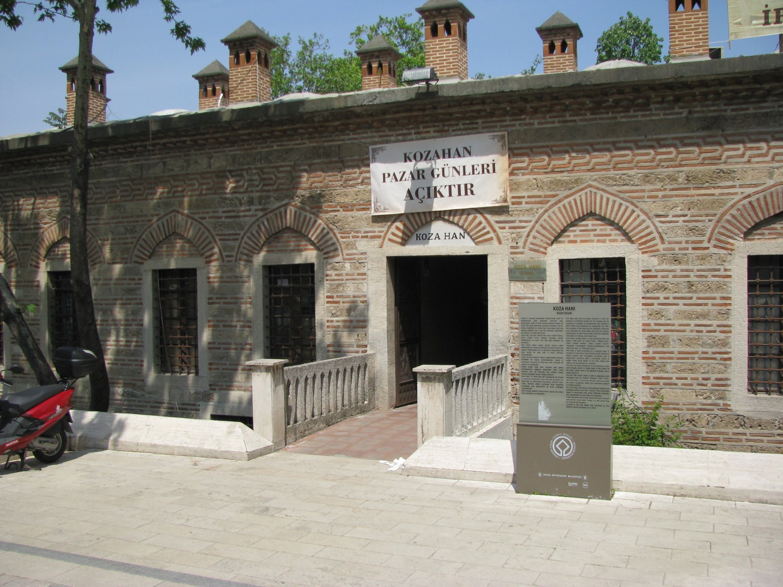 An entrance to Koza Han in Bursa, photographed in 2010. Visible opening signage is historical, not current visitor information.