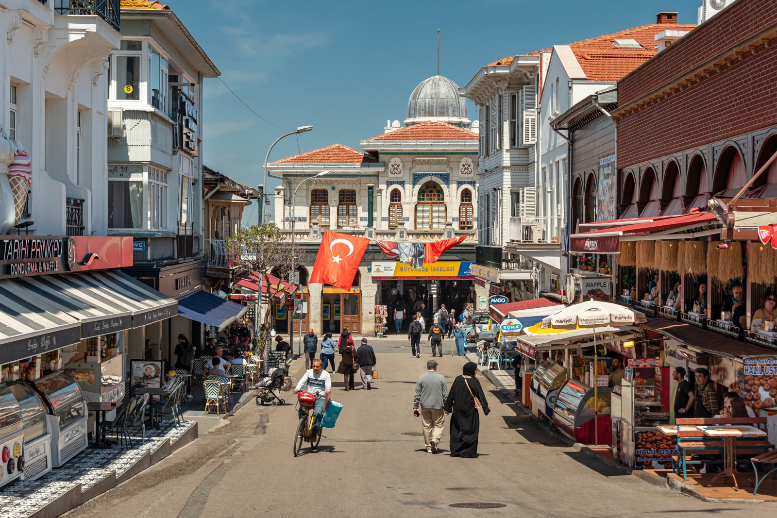 Shops and cafés frame Büyükada’s ferry terminal, May 2025.